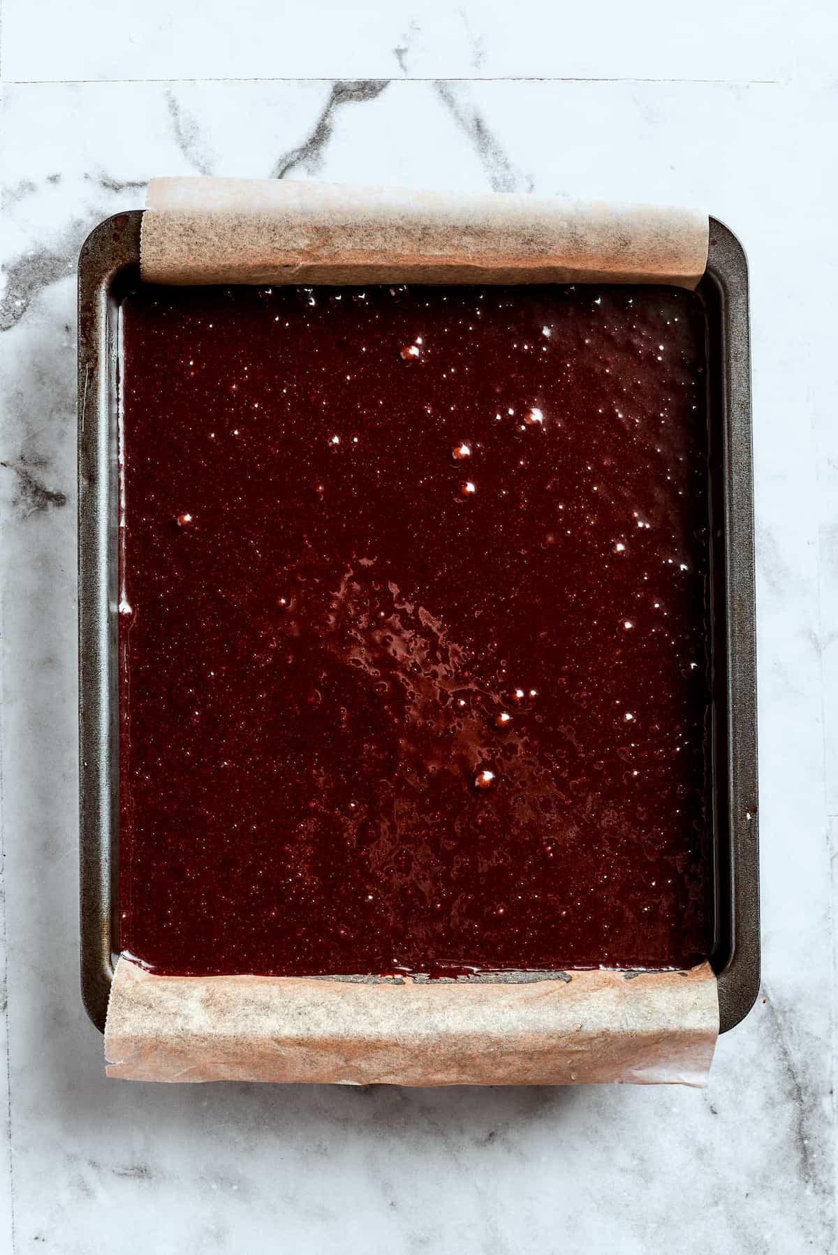 Brownie batter is spread into a baking pan.