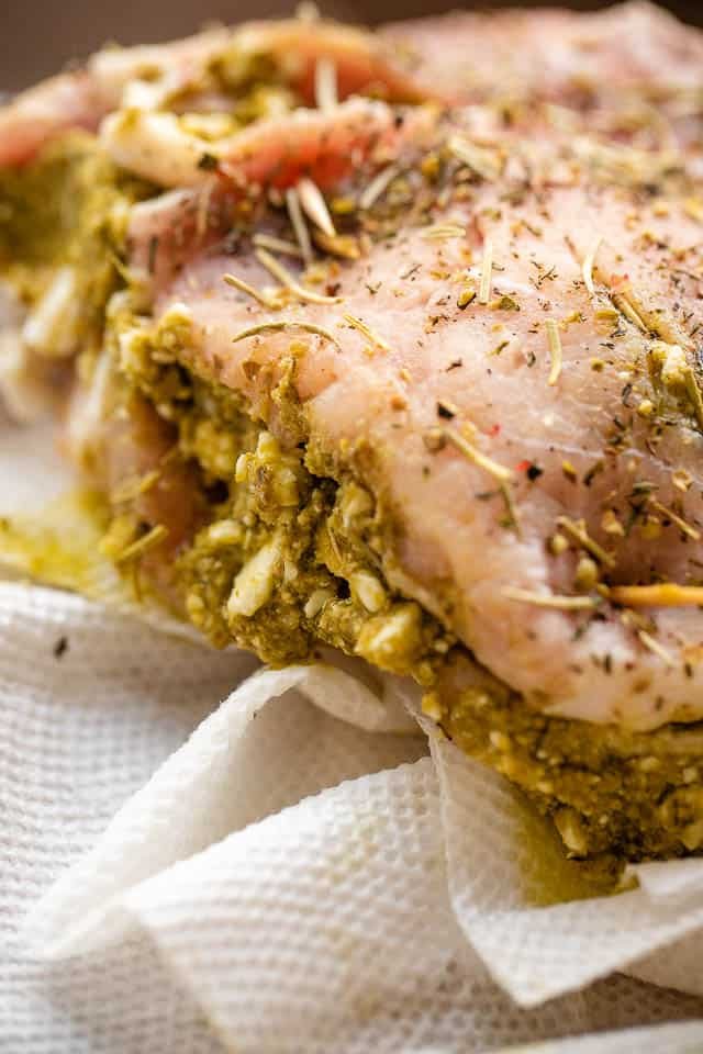 side shot of raw pork chop stuffed with pesto and feta cheese