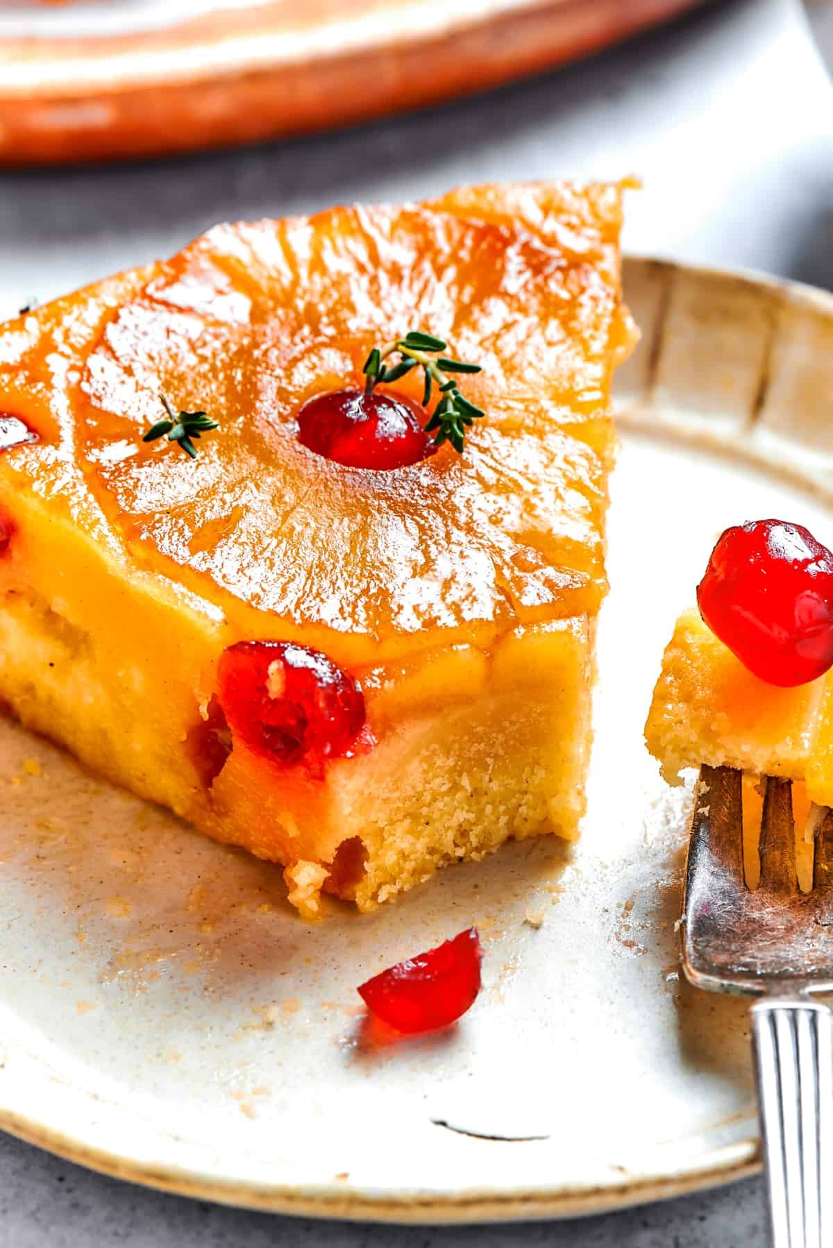 Slice of pineapple cake served on a dessert plate, with a fork next to it holding a bite of cake.