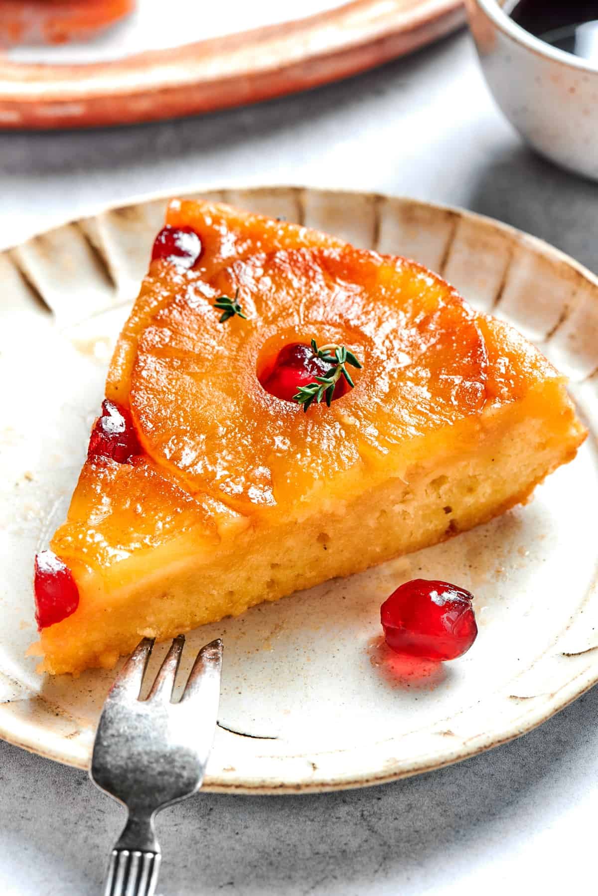 Slice of pineapple upside down cake served on a plate with a fork next to it.