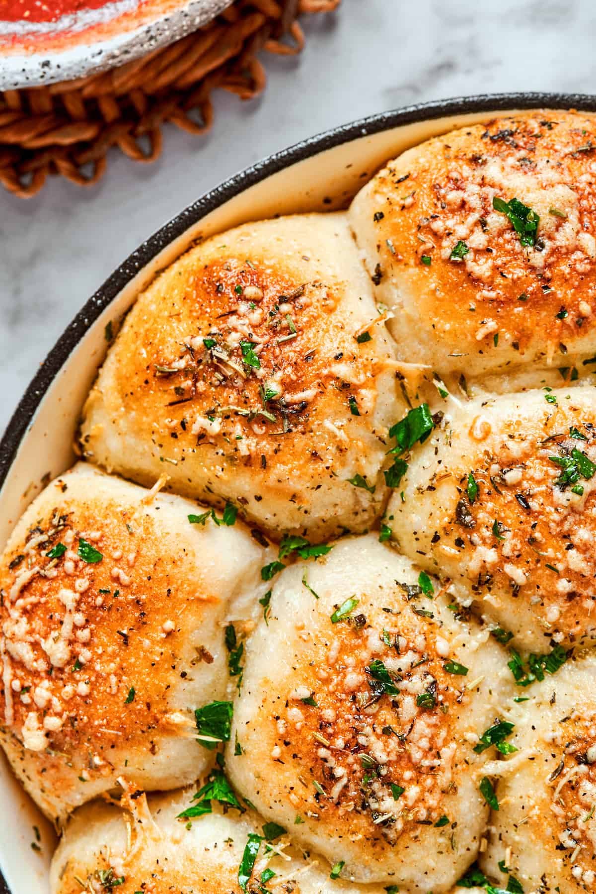 Half of the skillet of baked pizza bites topped with herbs.