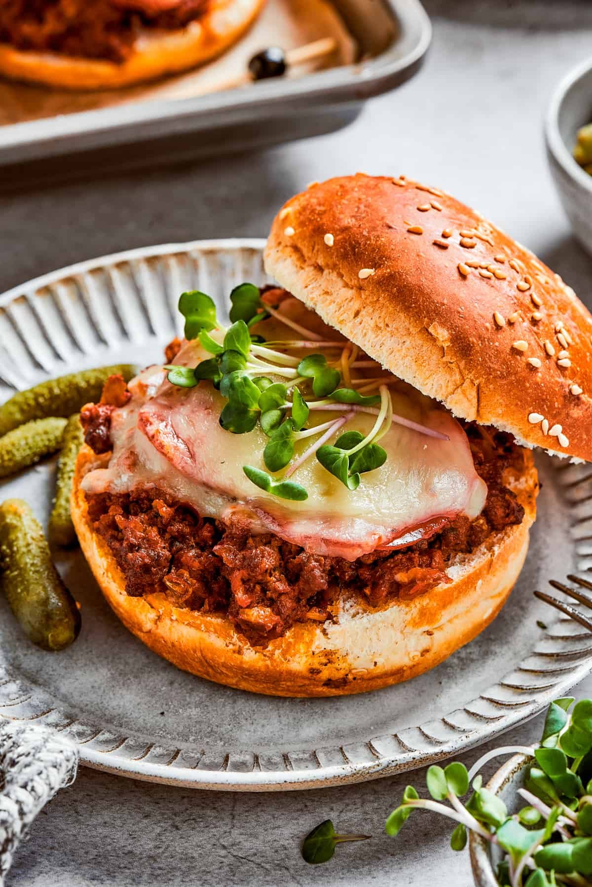 Pizza burger with the top bun resting on the side of the burger so the filling is exposed.