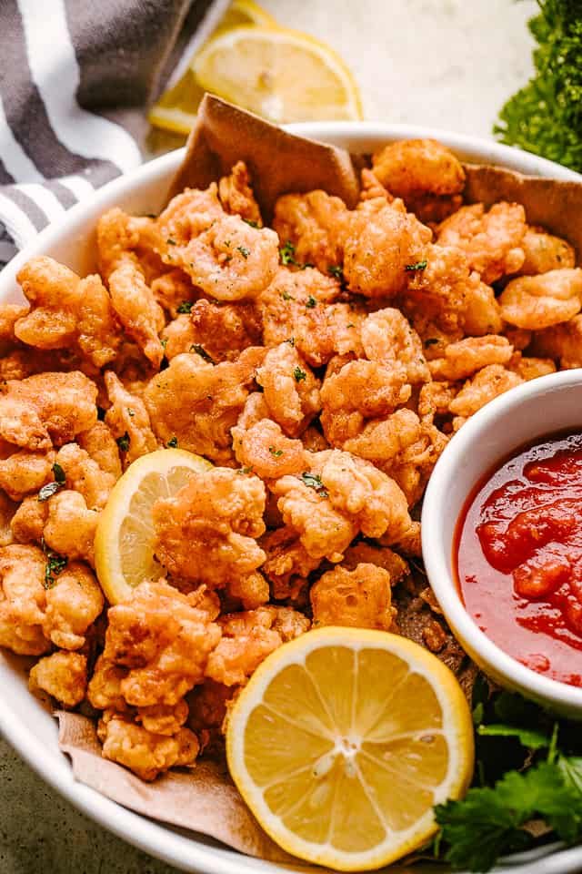 Popcorn shrimp on a plate with lemon and dipping sauce