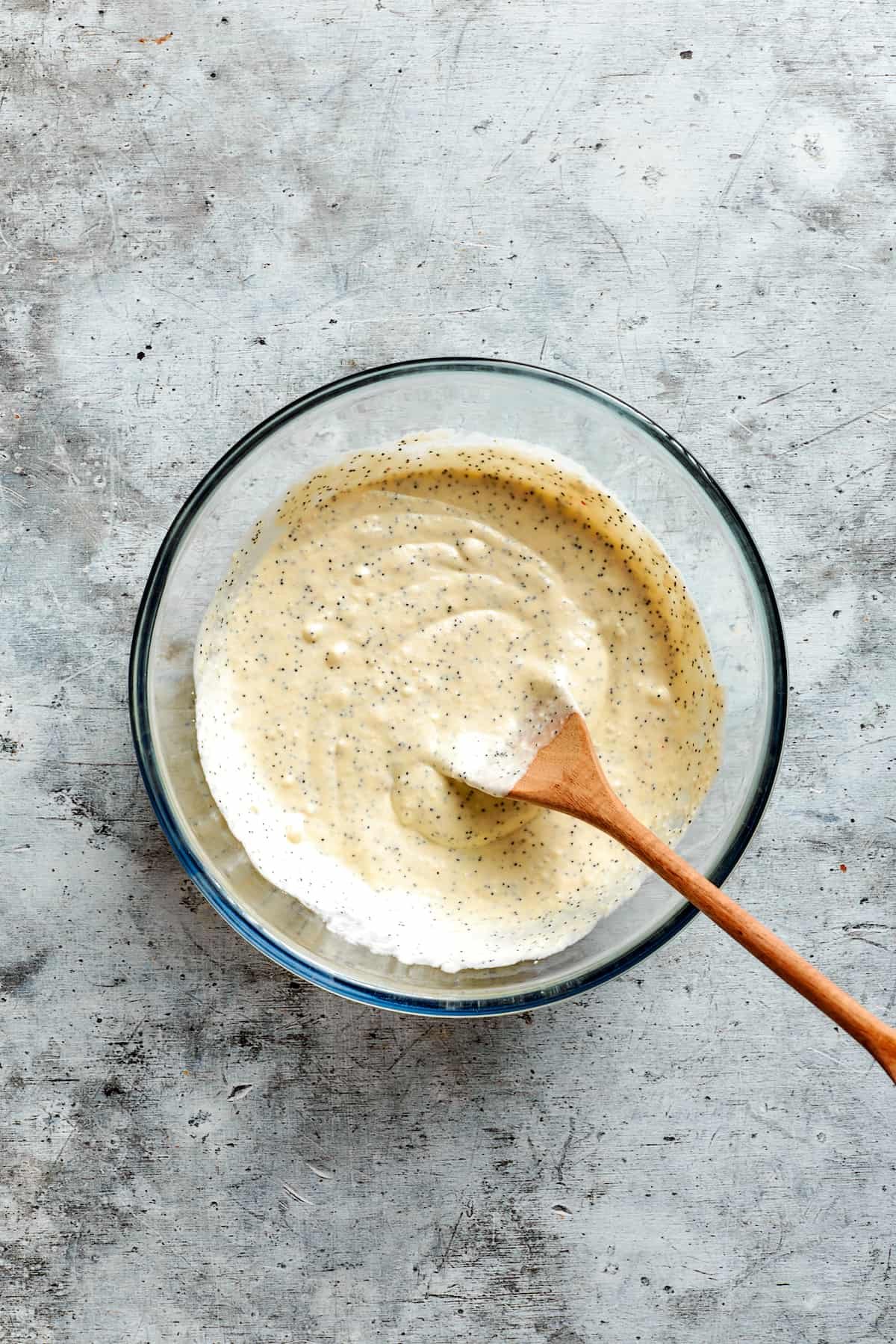 A wooden spoon stirs the sauce together.