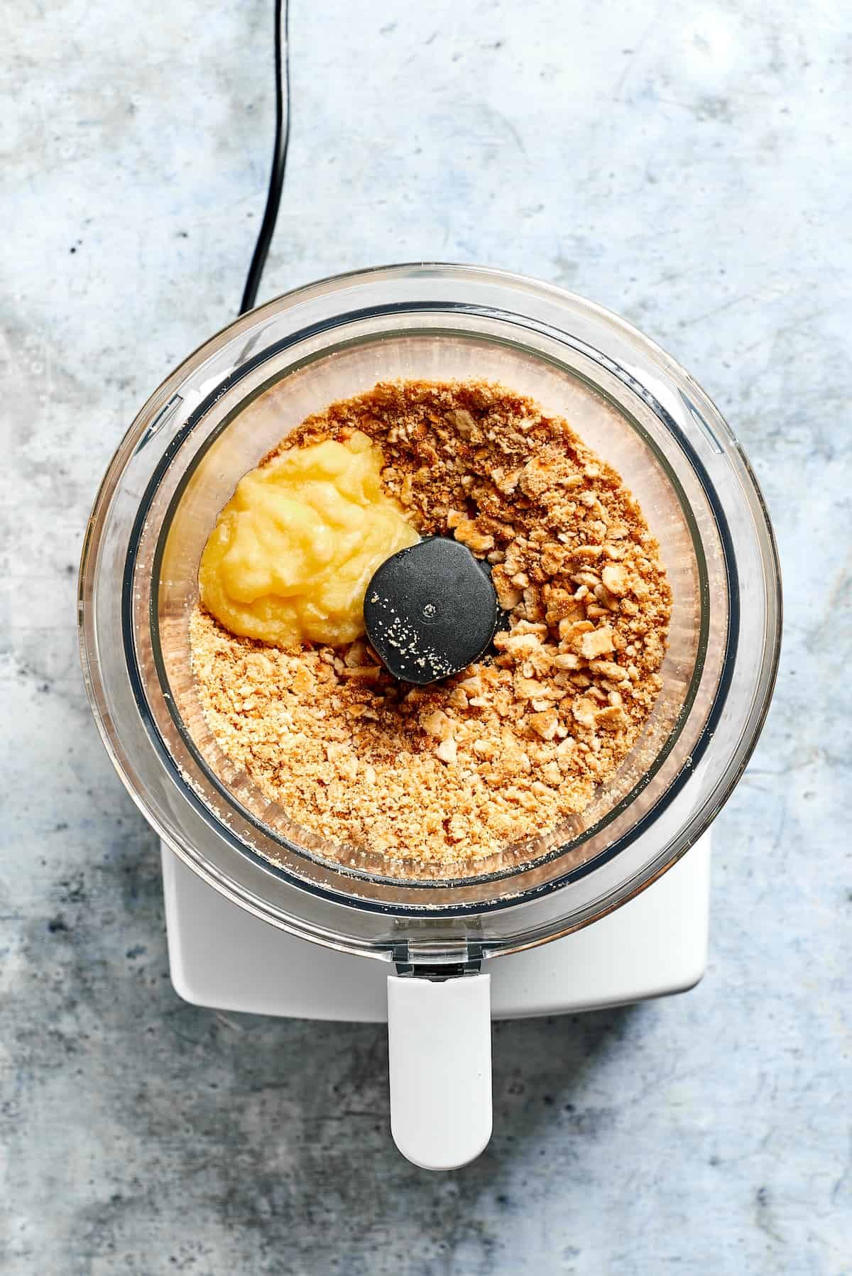 Ritz crackers and butter are placed in a food processor.