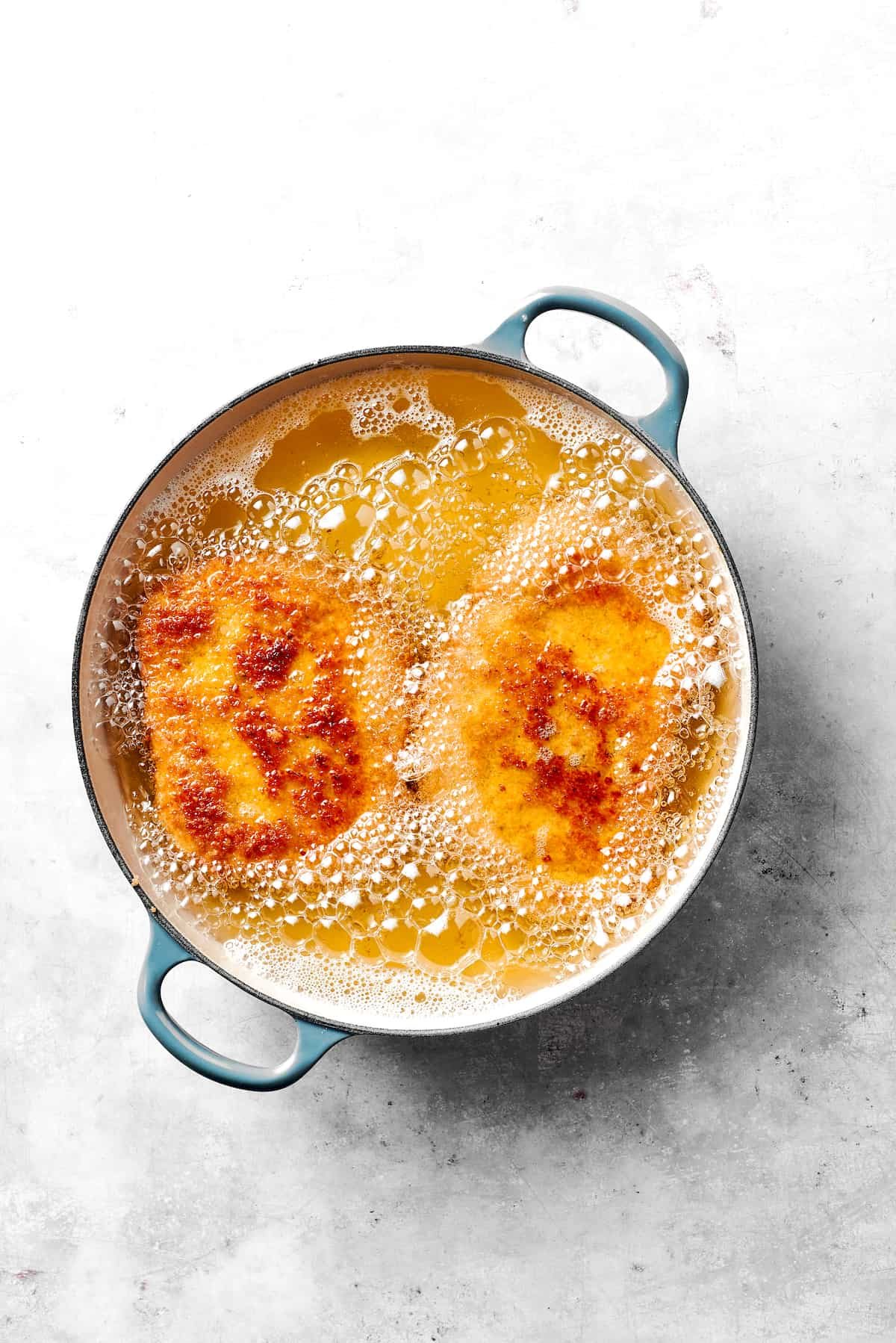 Pork cutlets frying in oil.