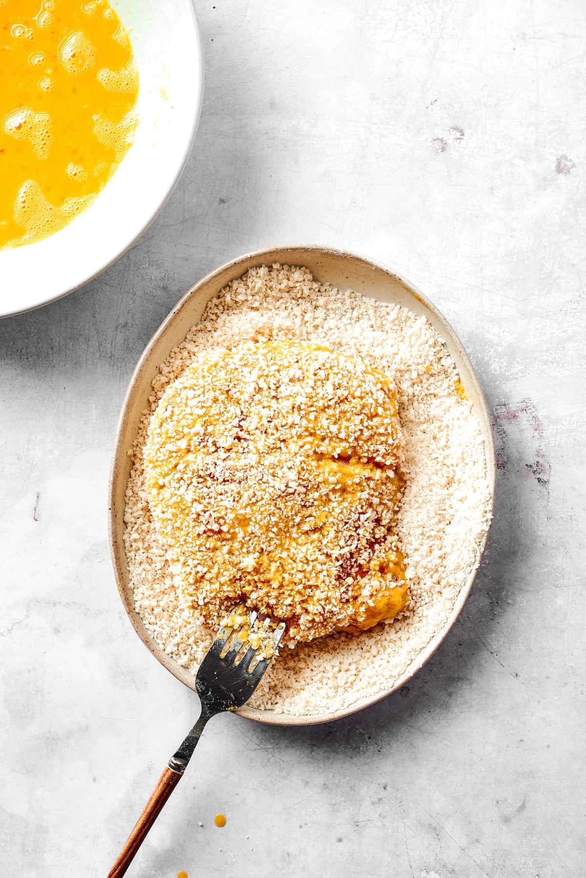 Dredging pork cutlets in breadcrumbs.