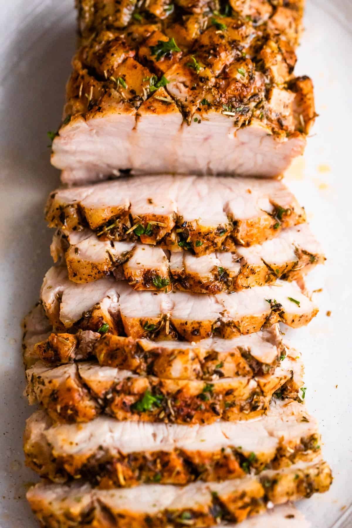 overhead shot of cooked and sliced pork roast set on a white background