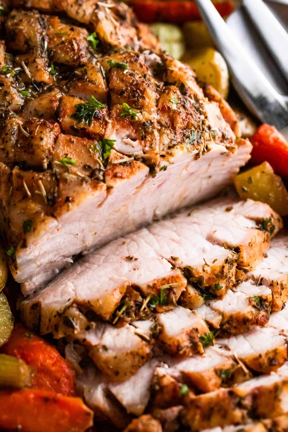up close shot of baked pork loin roast sliced and served with vegetables