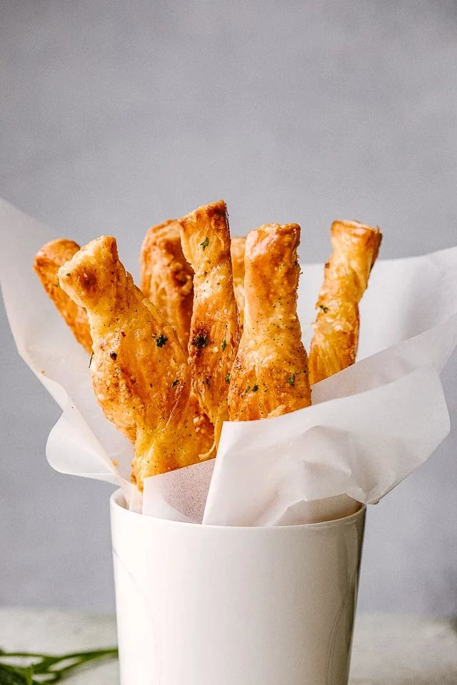 Puff Pastry sticks ready to serve in a white cup.