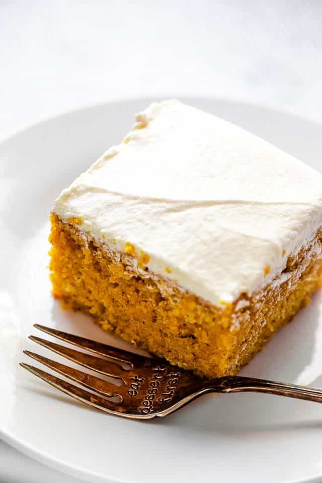 side shot of frosted pumpkin bar on a plate with a fork next to it