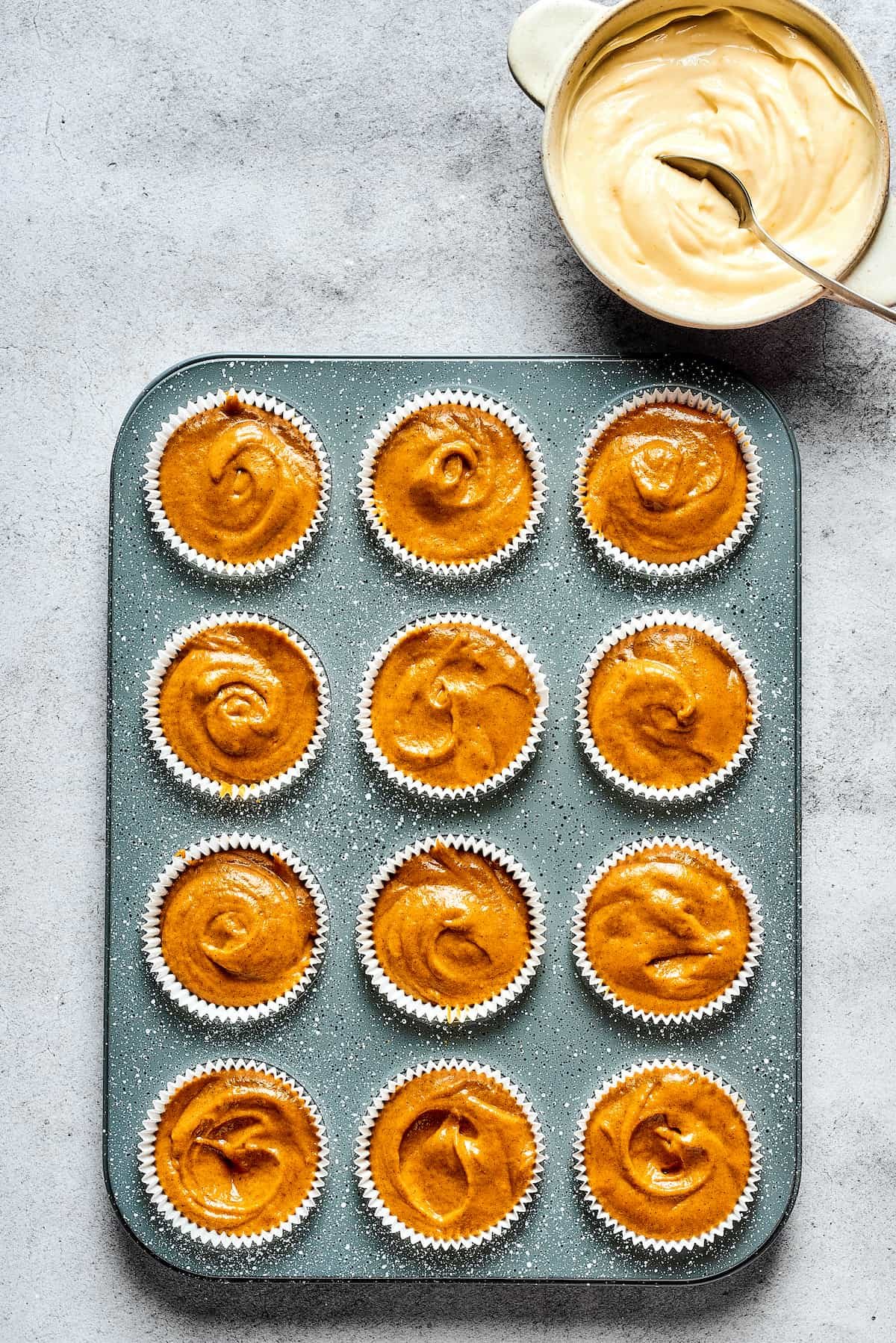 A muffin tin with muffin batter poured into paper liners.