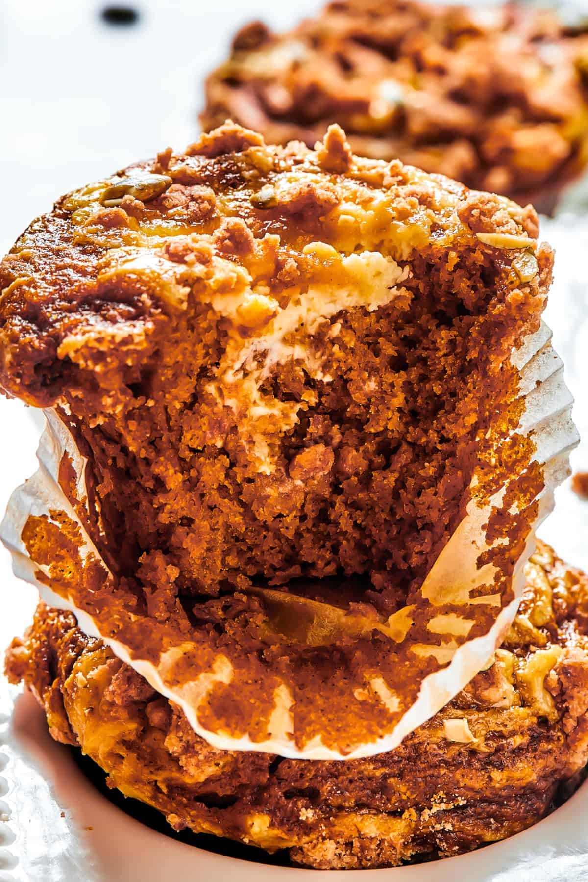 A pumpkin muffin broken in half with the paper muffin cup peeled away.