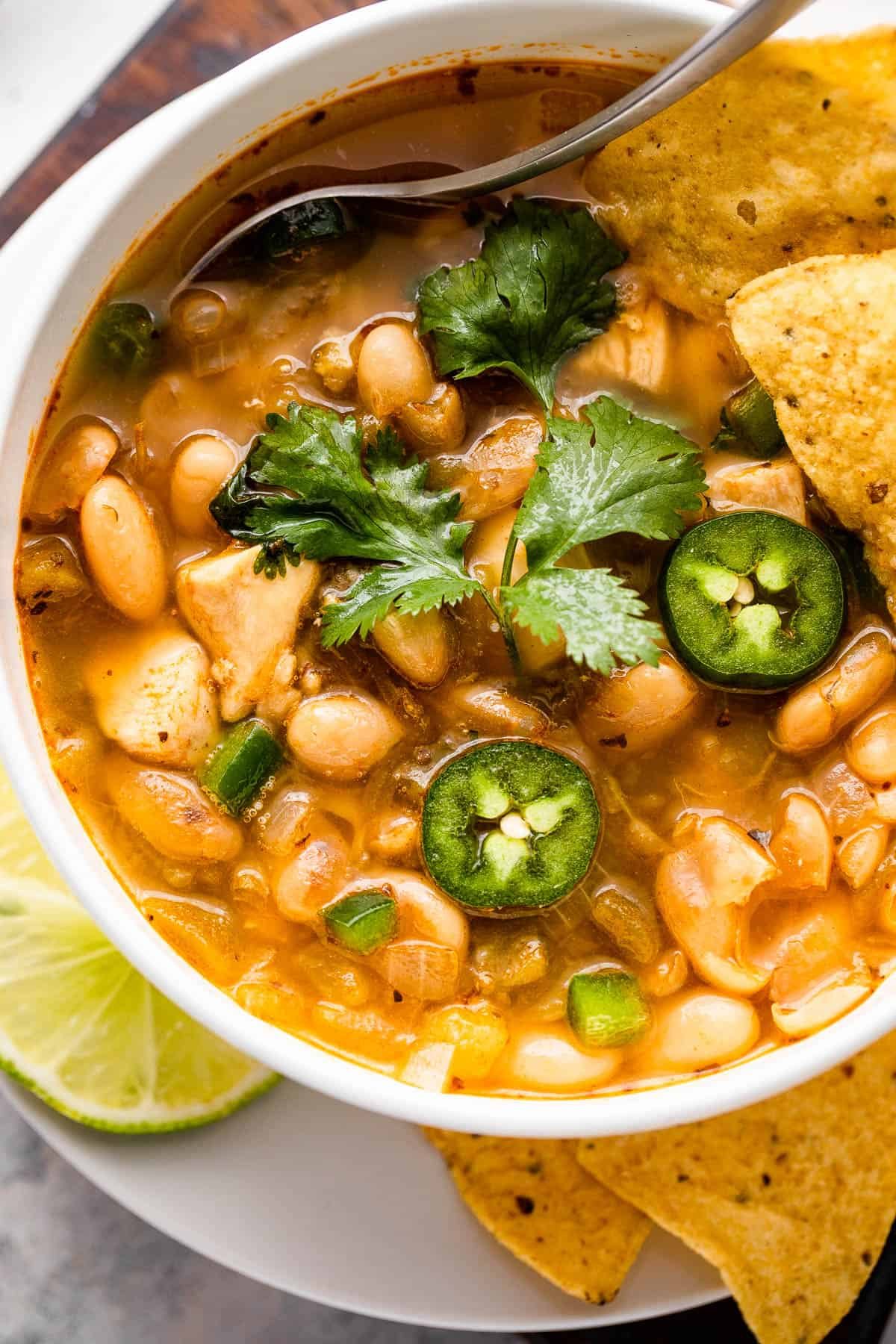 chicken chili in a bowl topped with jalapenos, cilantro, and tortilla chips