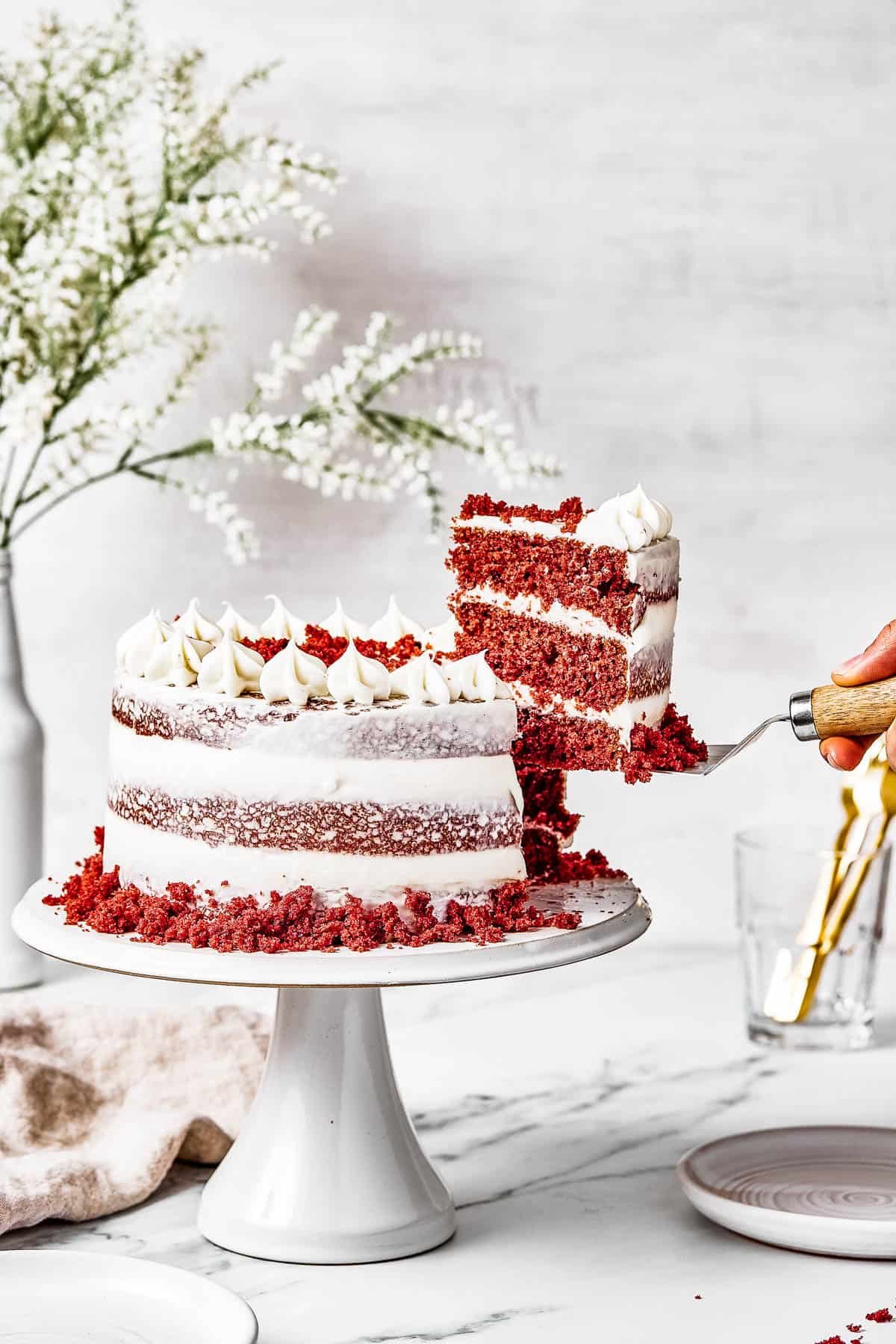 A woman's hand is lifting a slice of cake on a serving utensil.