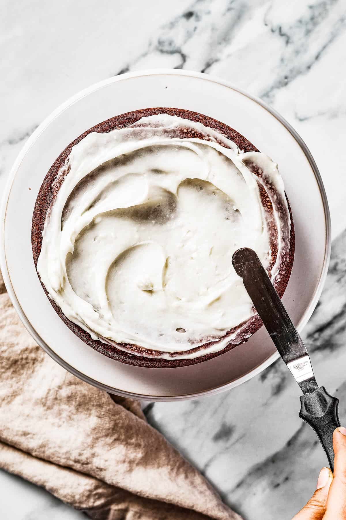 Overhead shot of a cake being frosted with an offset spatula.