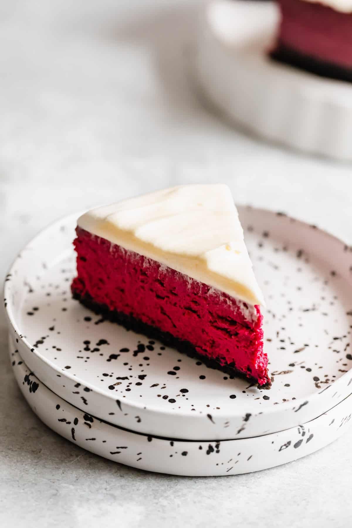 A Slice of Homemade Cheesecake with Oreo Crust and Cream Cheese Frosting on a Dessert Plate