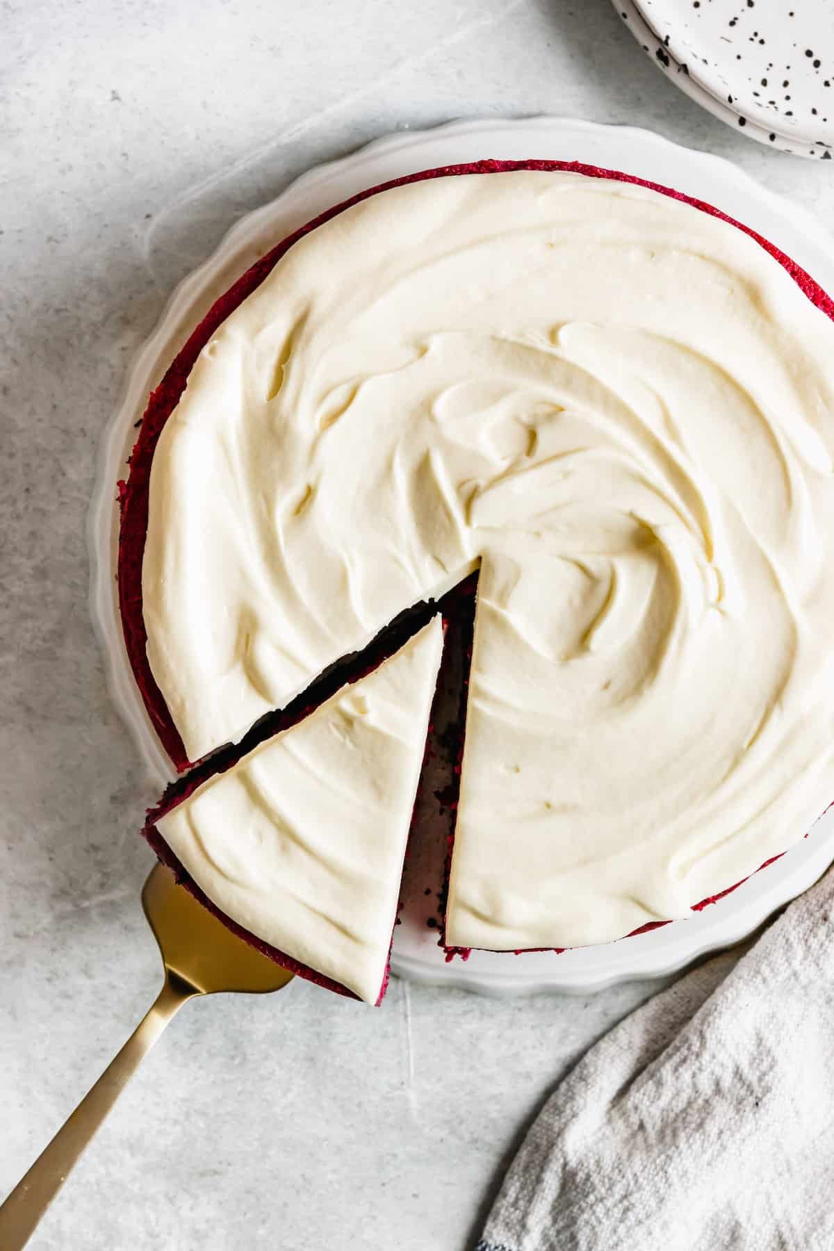 A Frosted Red Velvet Cheesecake Shown From the Top with One Slice Being Removed