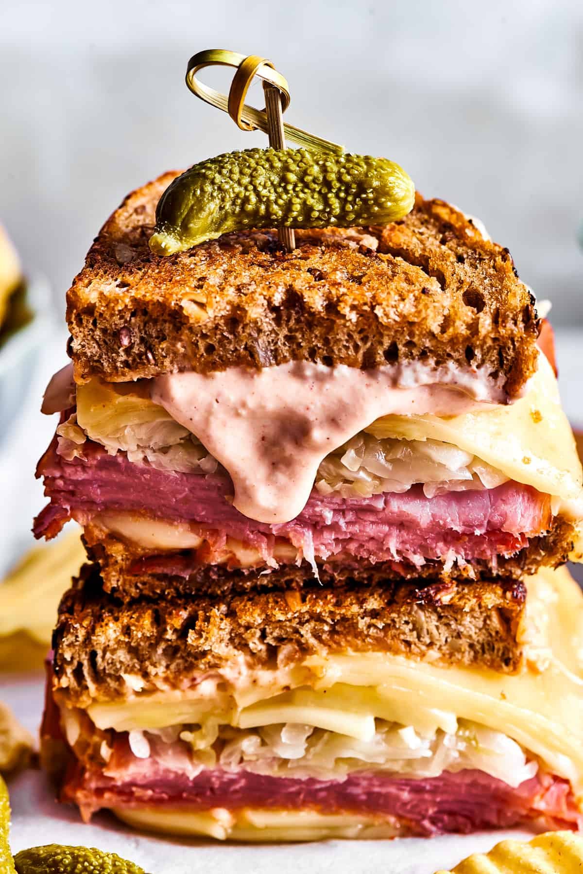 Two Reuben sandwich halves with Russian dressing dripping from one.