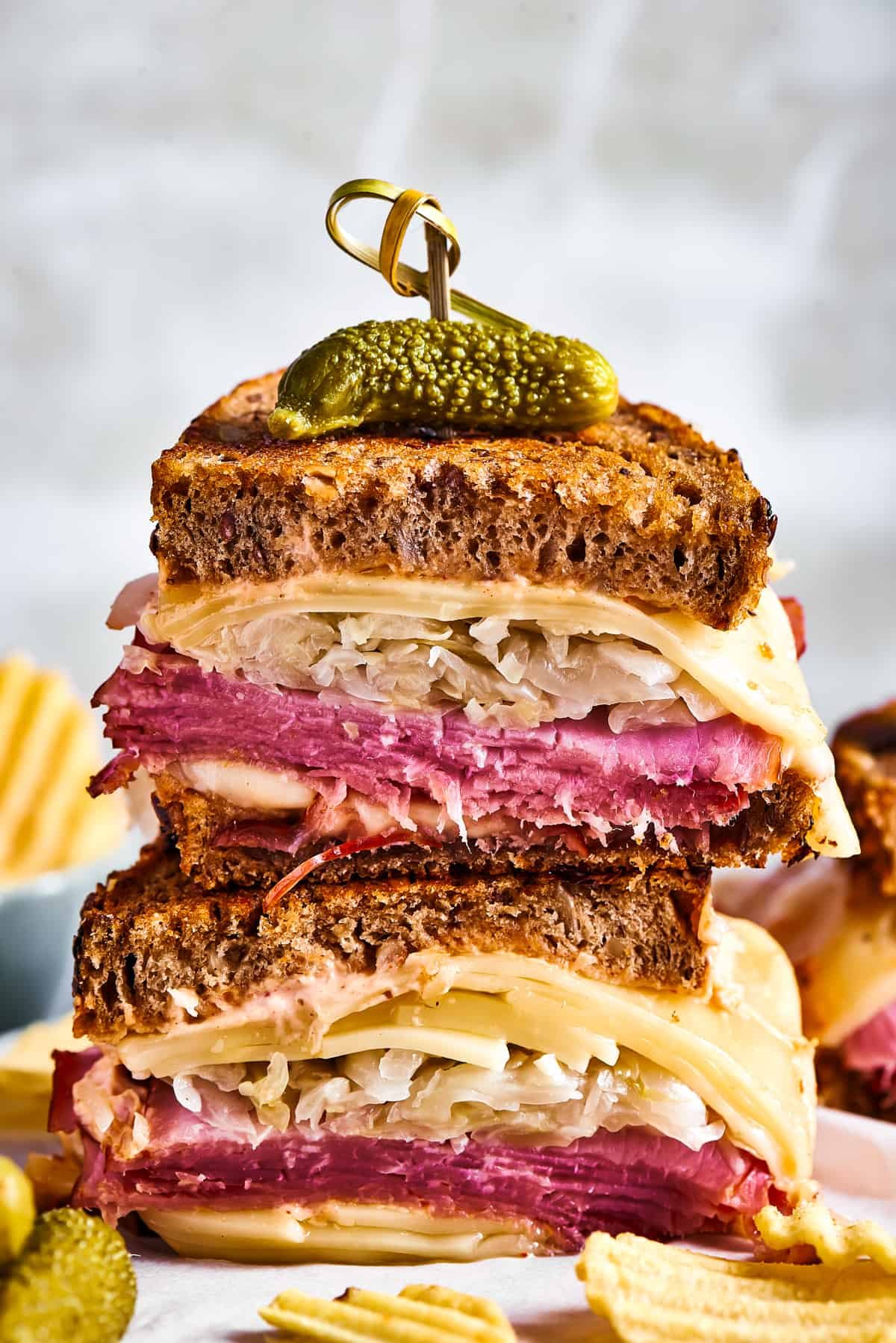Grilled sandwich halves stacked and topped with a pickle.