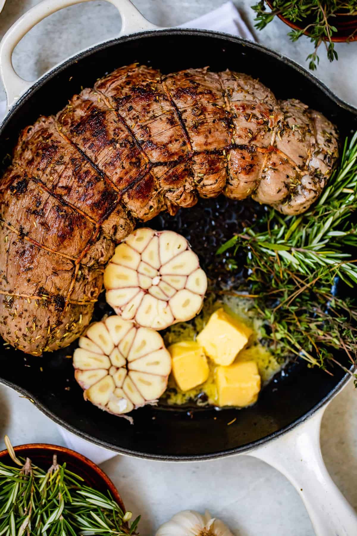 Roast Tenderloin, Garlic Cloves, Rosemary and Butter in a Metal Skillet