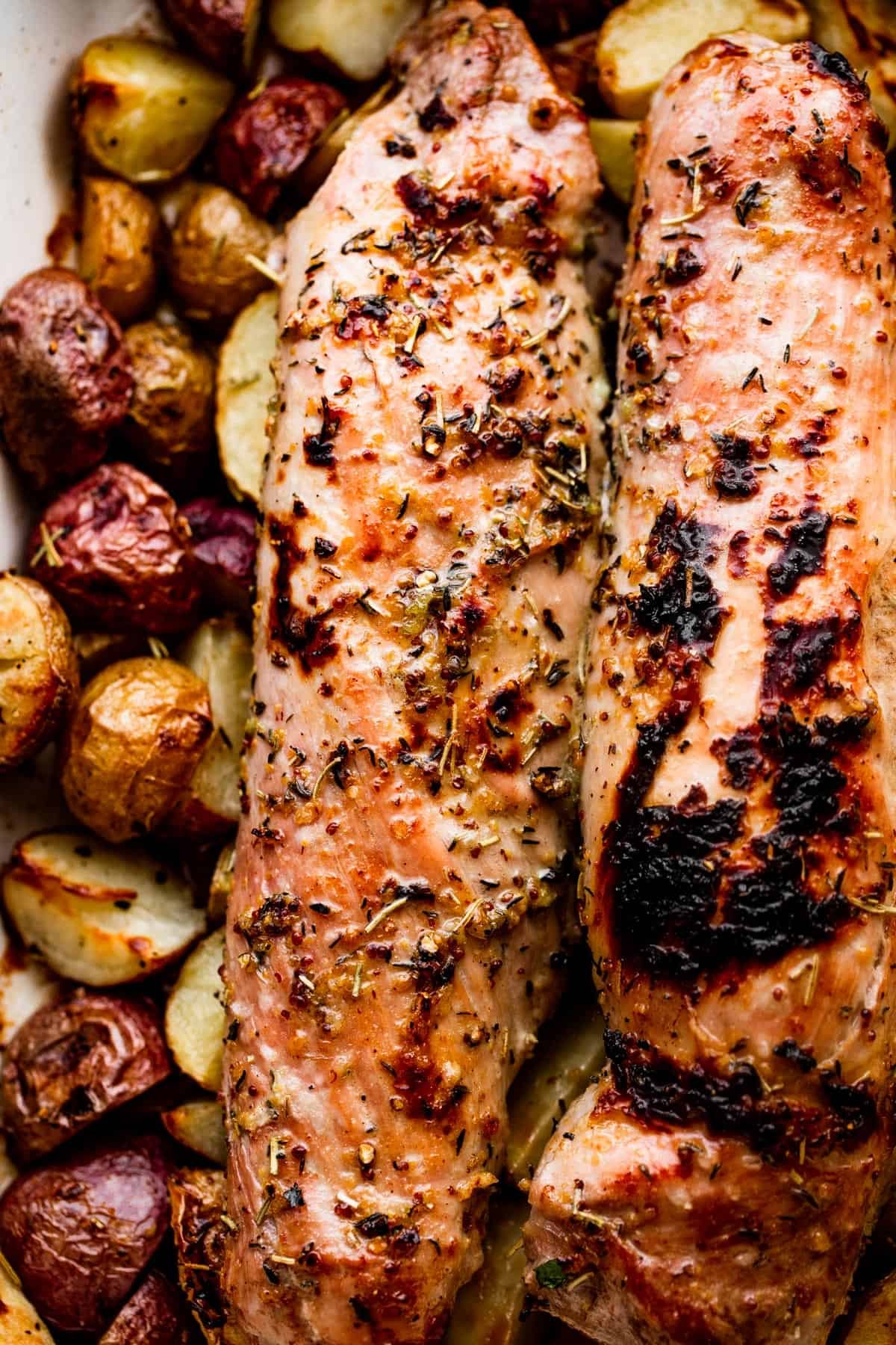 roasted pork tenderloins set on top of cooked baby potatoes