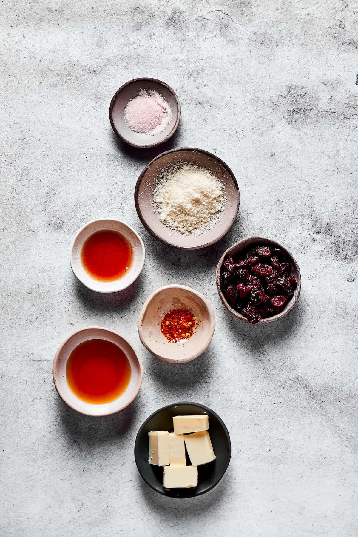 From top: Salt, parmesan cheese, dried cranberries, chili flakes, butter, maple syrup, pomegranate vinegar.