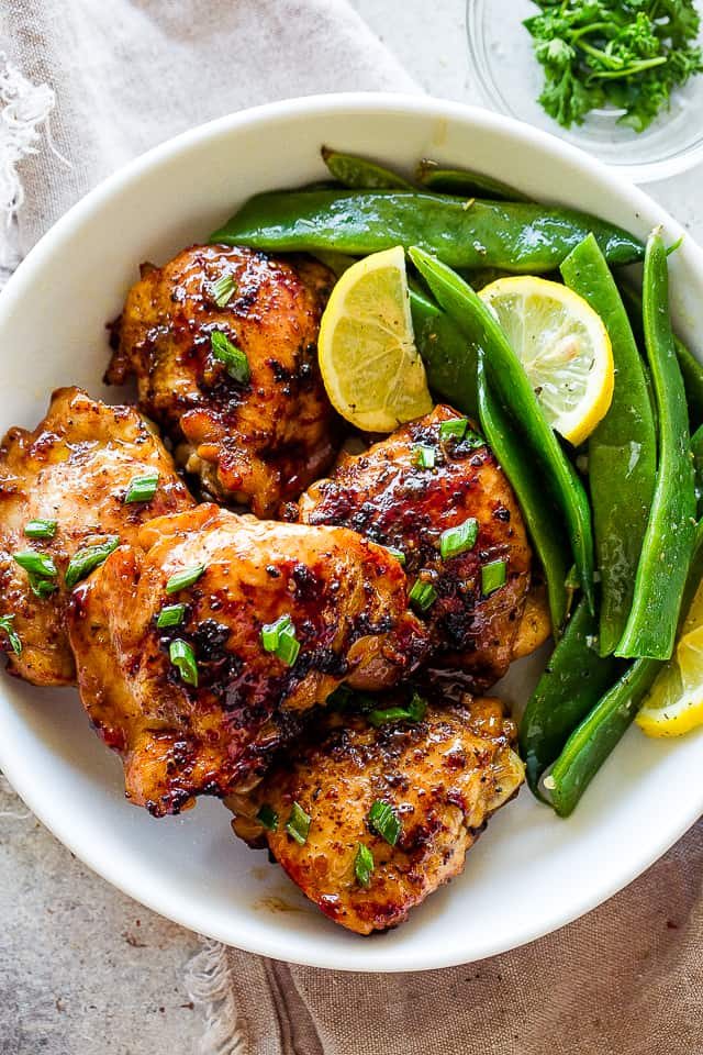 Romano flat beans served on a plate with browned chicken thighs.