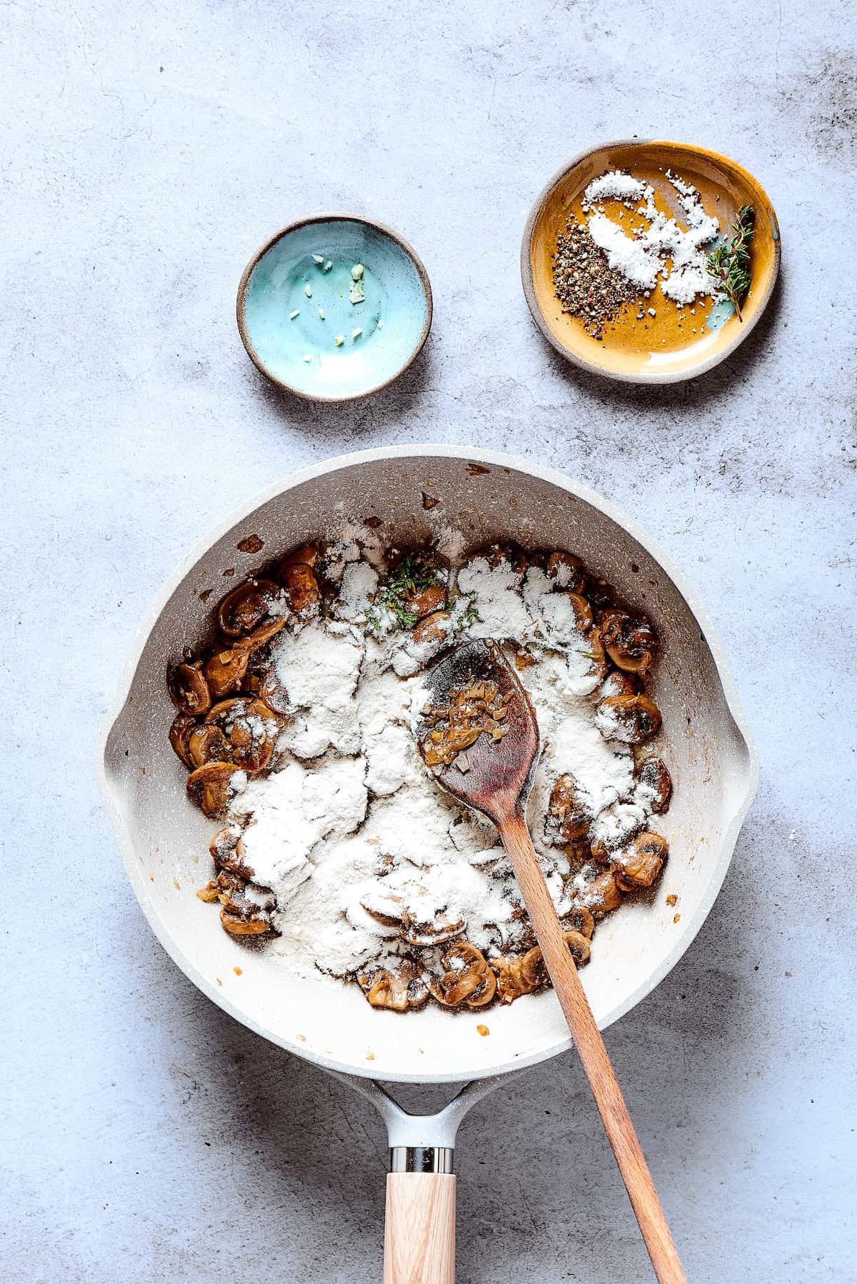 Flour sprinkled on top of cooking vegetables in a skillet.