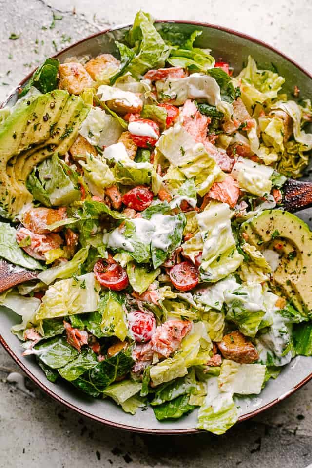 Salmon BLT salad plated with dressing mixed throughout