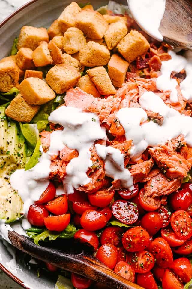 Salmon BLT salad plated and topped with dressing