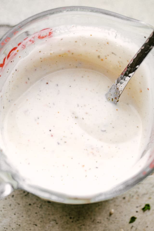 A mayonaise based dressing for Salmon BLT salad in a mixing cup with a spoon
