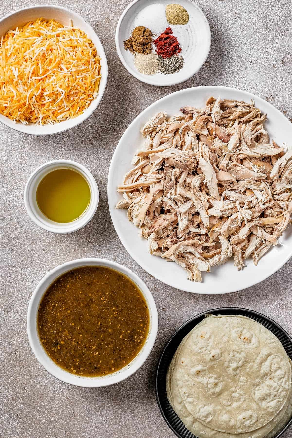 Clockwise, from top left: Shredded cheese, spices, shredded chicken, tortillas, salsa verde, olive oil.