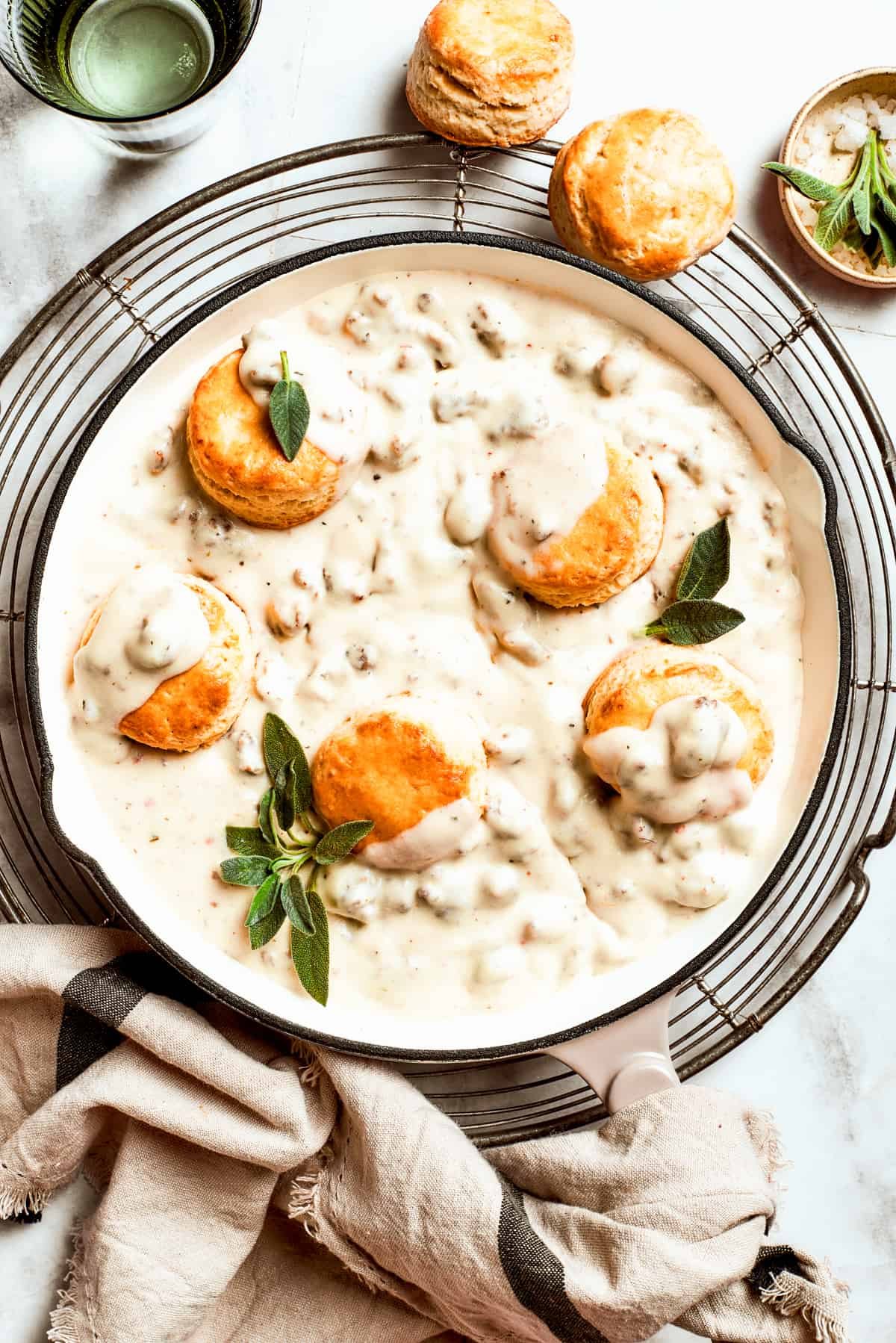 Five biscuits rest in a pan of sausage and gravy.