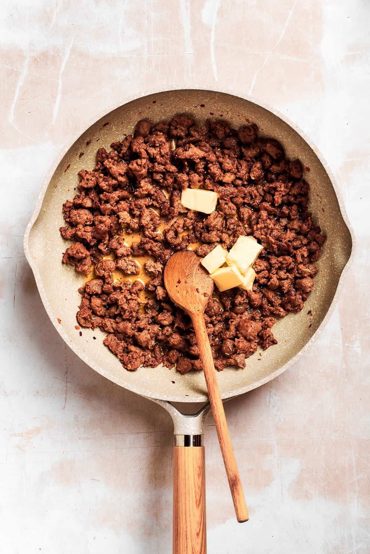 Butter is added to the sausage in the pan.