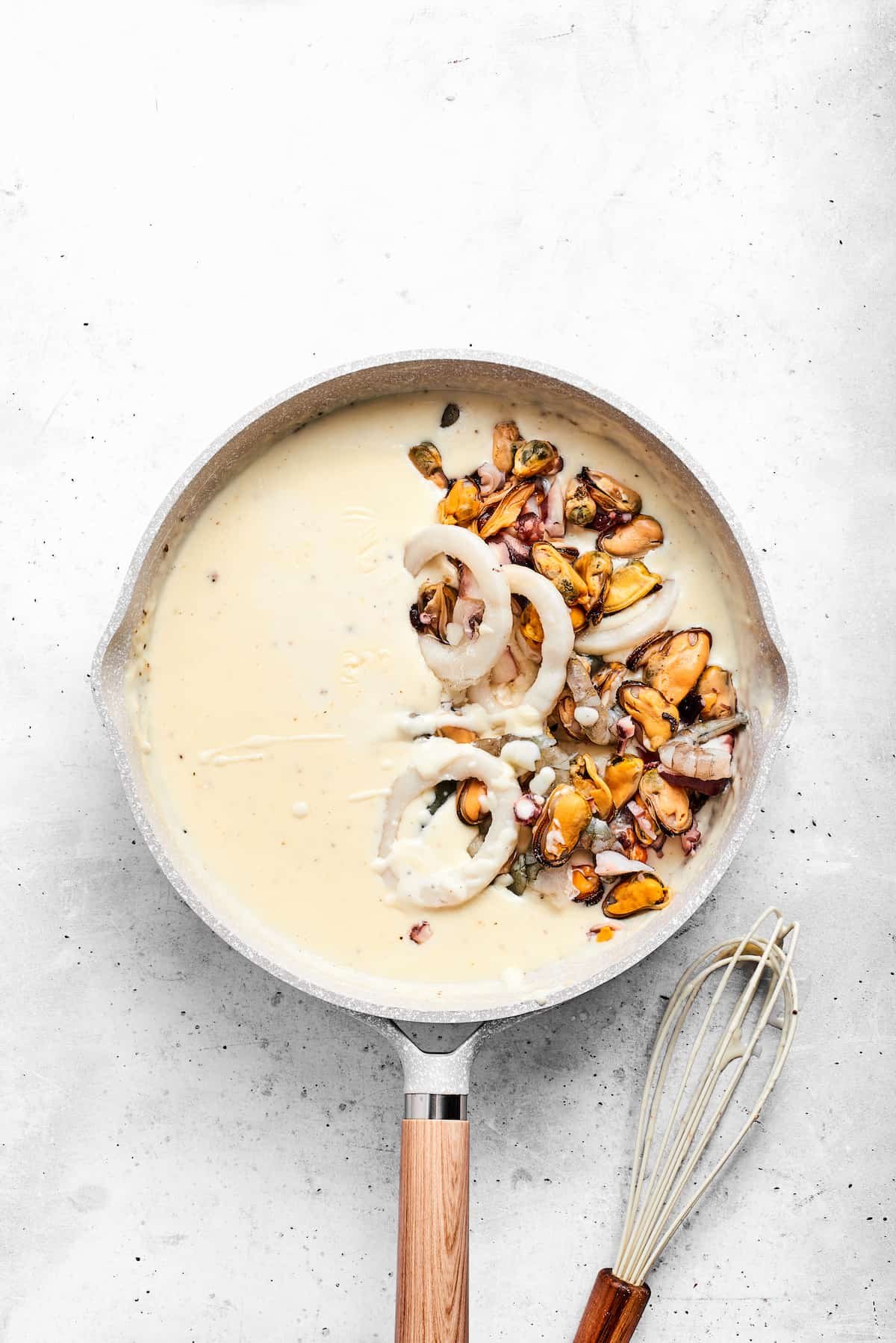 Adding seafood to the sauce.
