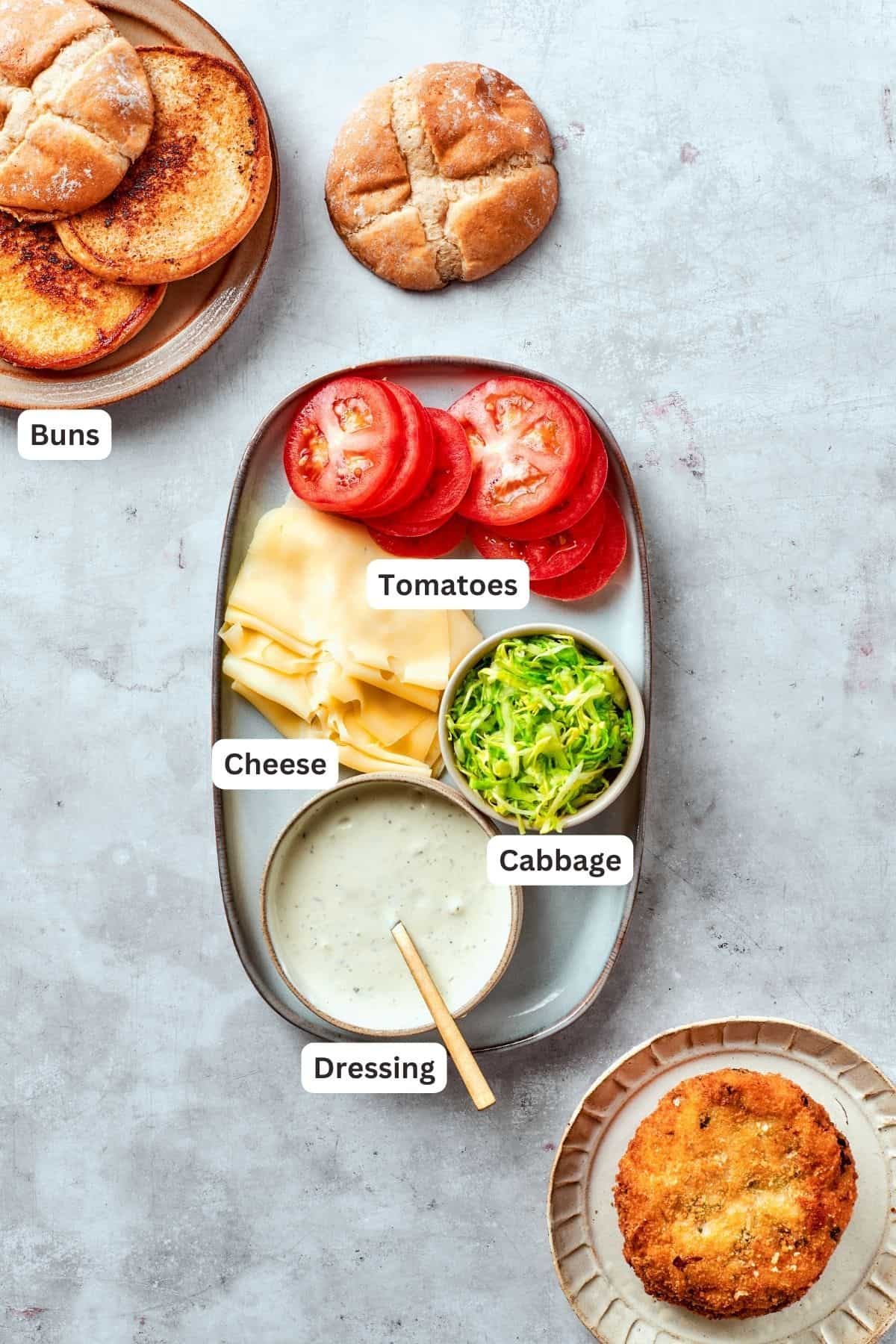 Ingredients for shrimp burgers assembly are shown labelled: buns, tomatoes, cabbage, dressing.