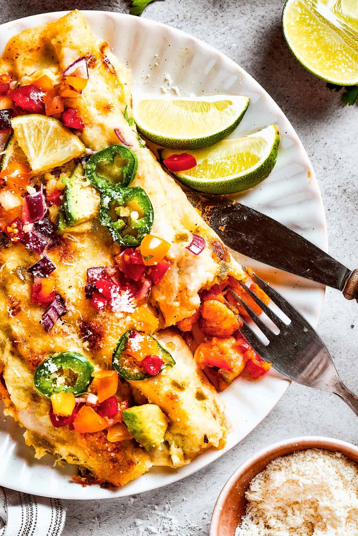 A plate of enchiladas topped with avocado and other toppings.