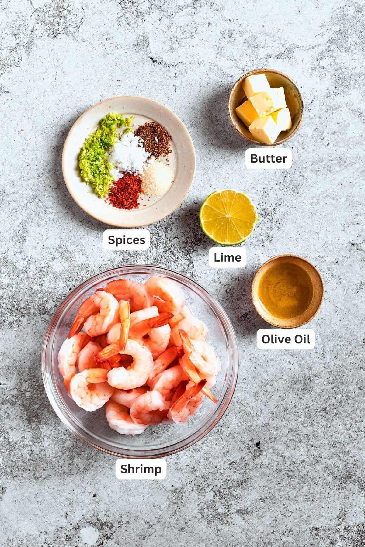 The ingredients for the shrimp are shown: shrimp, spices, butter, lime, olive oil.