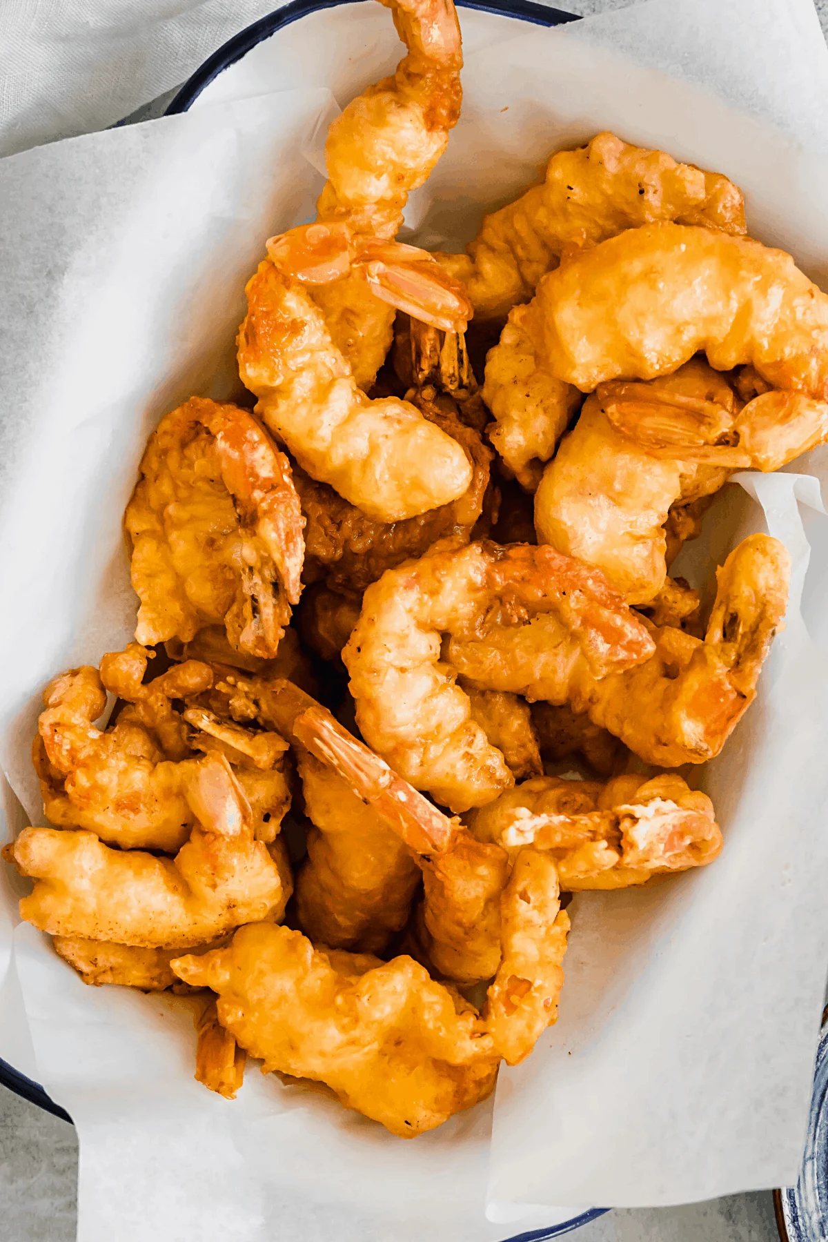 A White Serving Platter with a Blue Rim Holding Pan Fried Shrimp