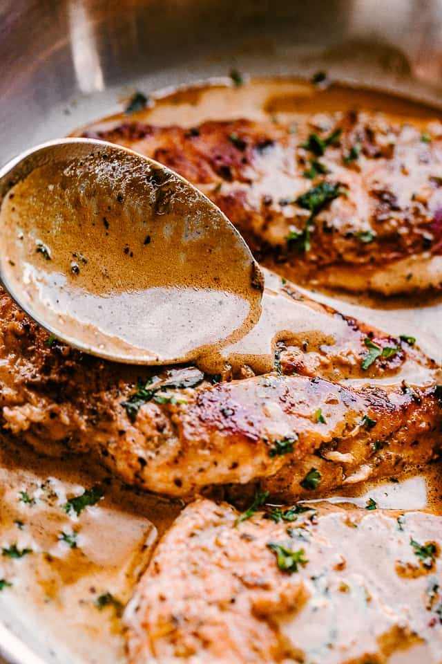 spooning creamy balsamic sauce over chicken
