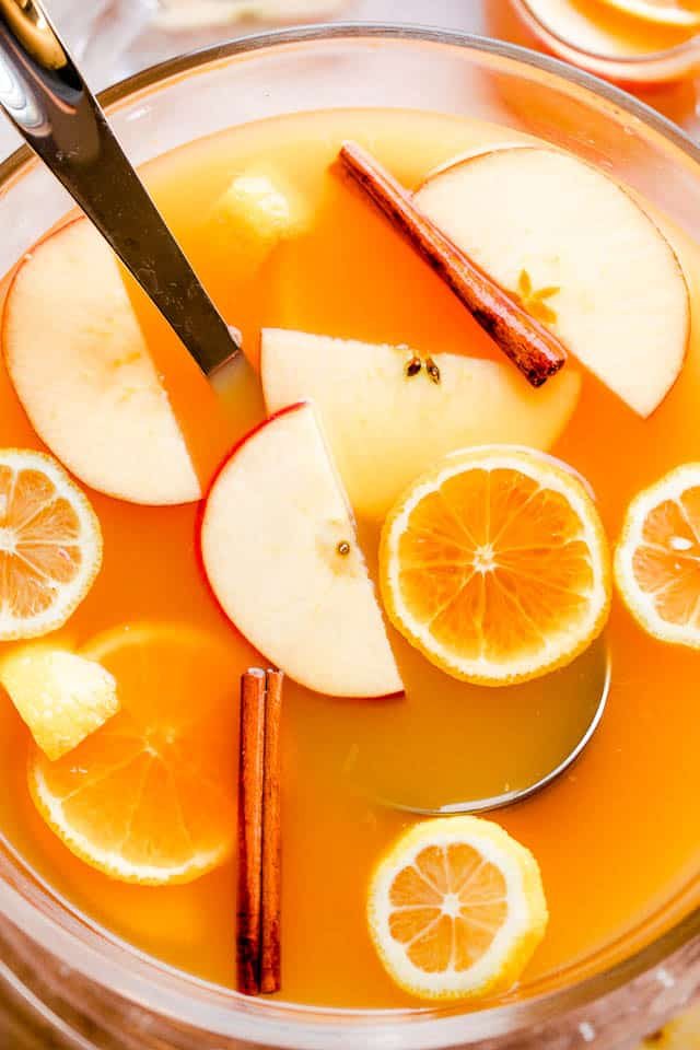 overhead shot of apple cider punch in a punch bowl with ladle and slices of fruit floating on top