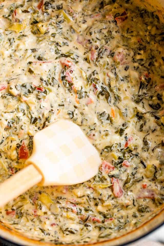 mixing spinach artichoke dip with a spatula