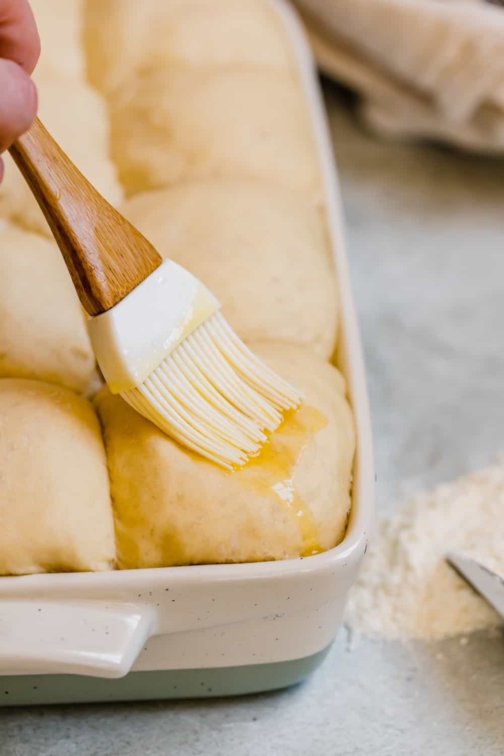 Butter Being Brushed Over Risen Parmesan Dinner Roll Dough