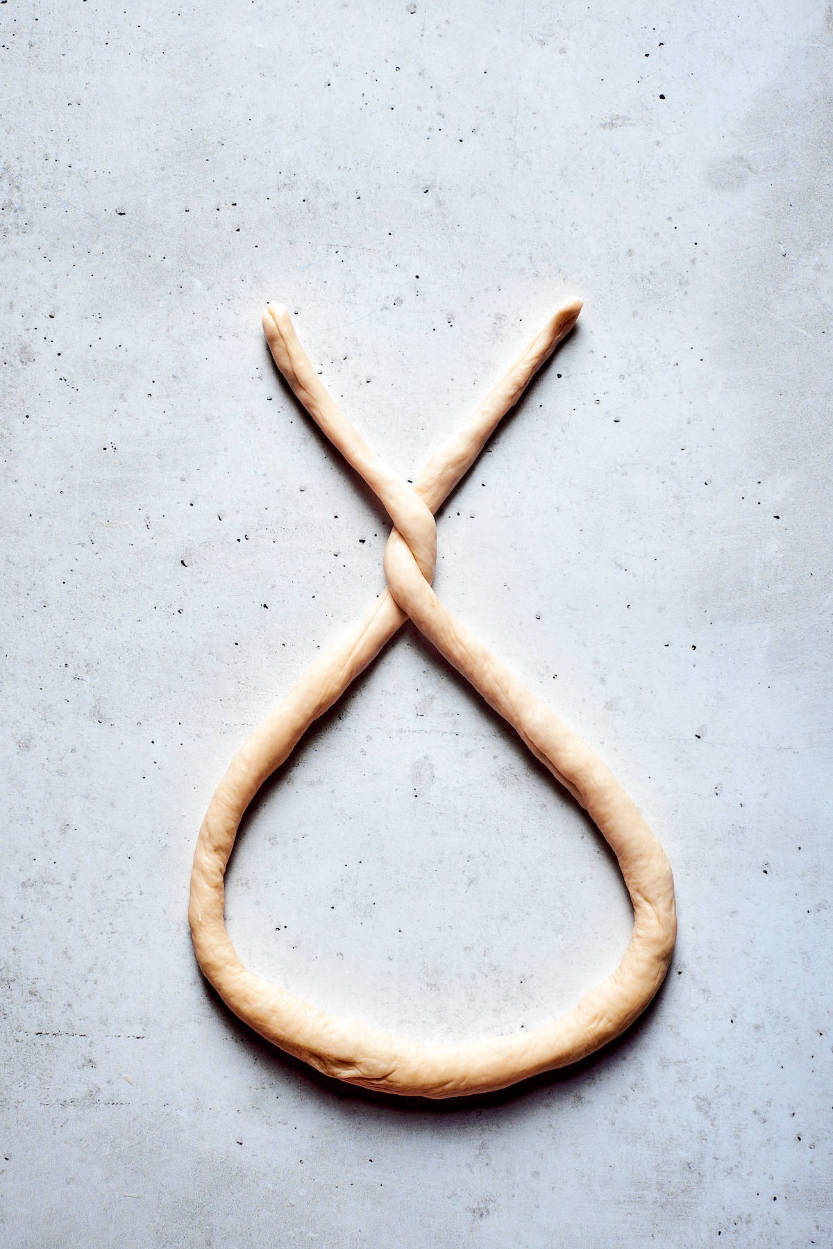 A rope of soft pretzel dough is formed into a pretzel.