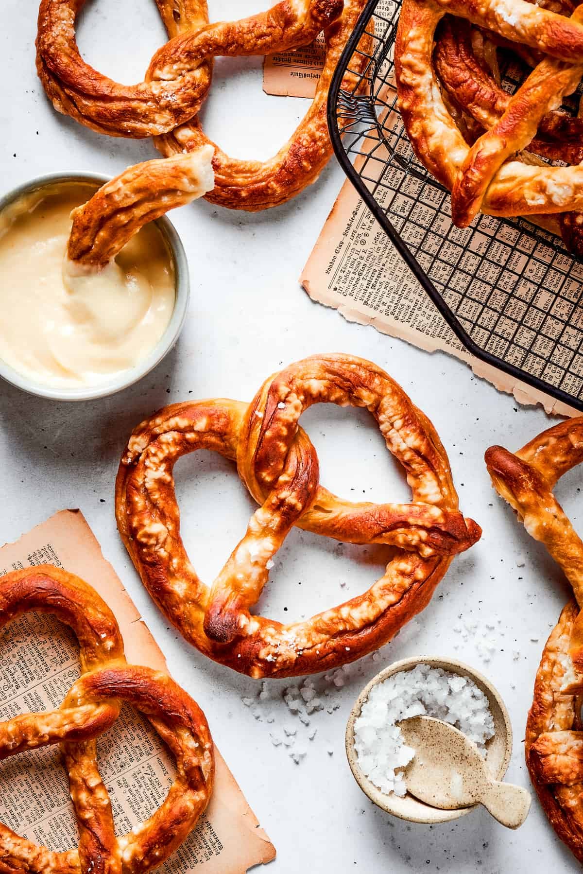 Baked soft pretzels are shown on a rack with cheese sauce alongside.