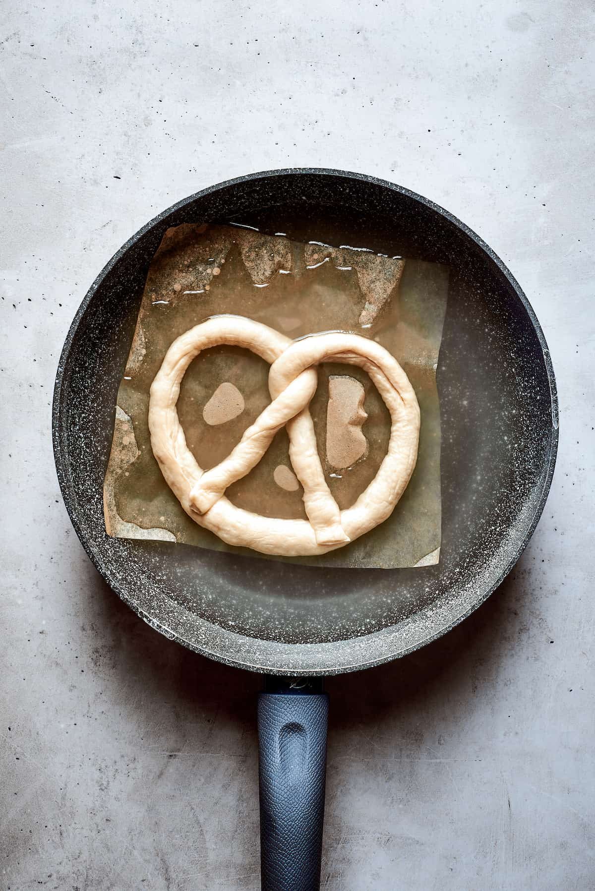 A top down shot of a soft pretzel in a pan.