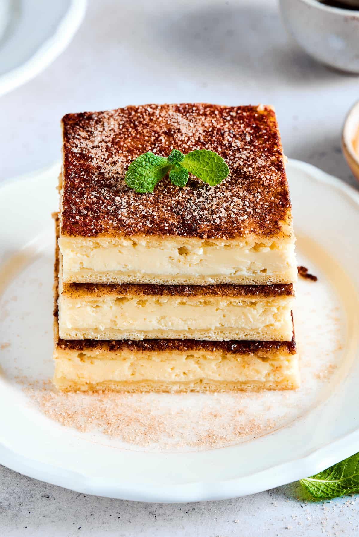 Three stacked cheesecake bars with cinnamon topping and mint leaves.