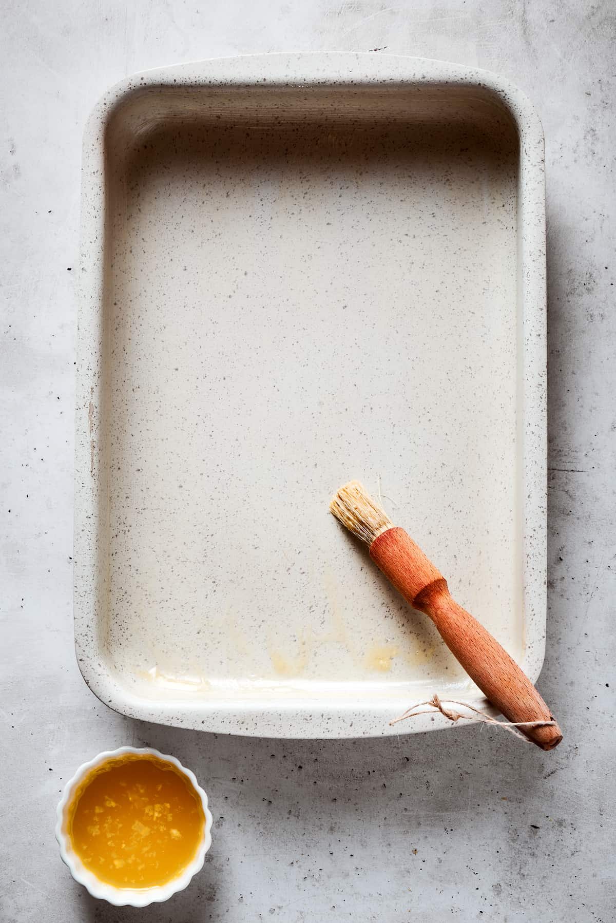 Brushing a baking dish with butter.