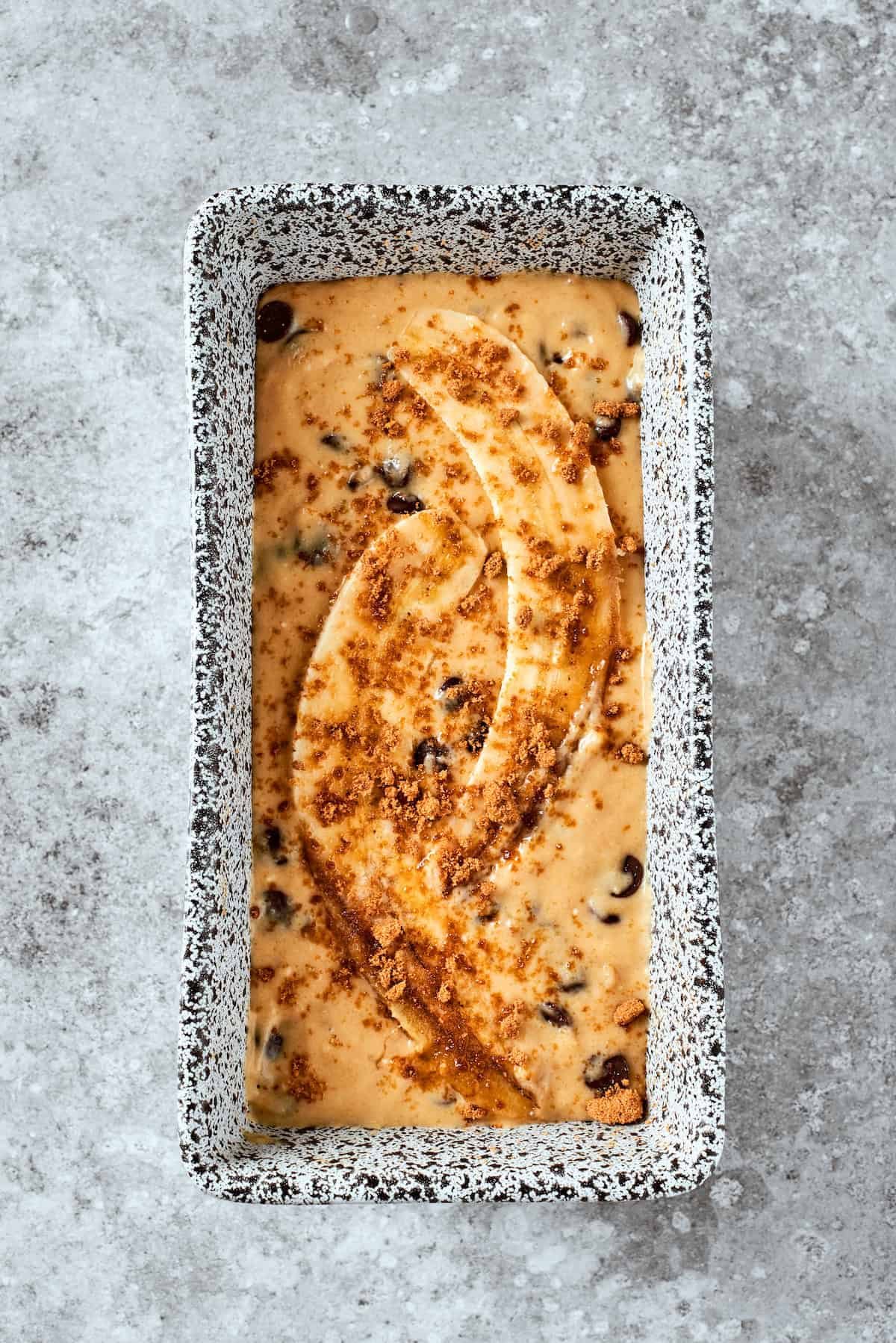 The bread batter is placed in a loaf pan and topped with bananas.
